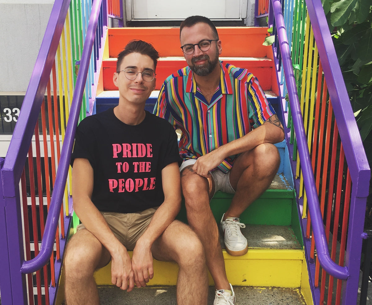 The Little Gay Shop team sitting on rainbow-painted steps in Austin, Texas